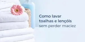 Toalhas brancas empilhadas com flor rosa e itens de lavanderia ao fundo