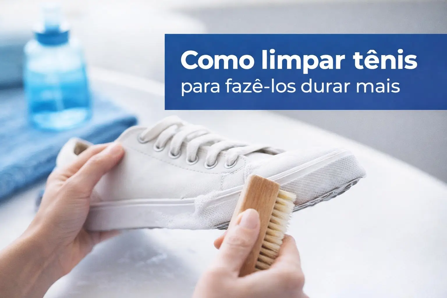 Pessoa limpando tênis branco com escova, produto e toalha azul ao fundo